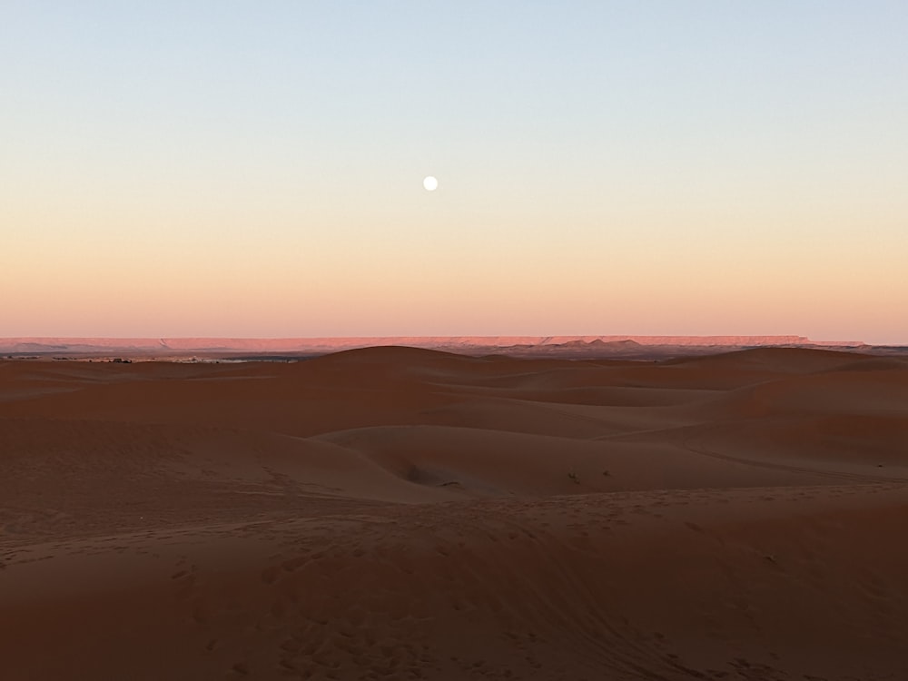 the sun is setting in the distance over the desert