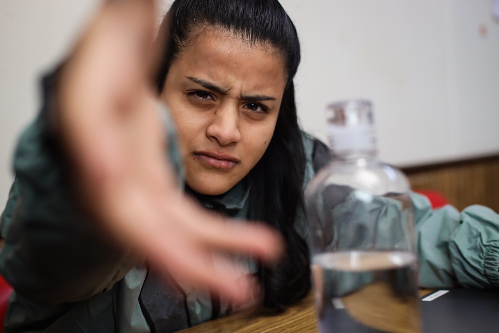 a woman sitting at a table with a bottle of water