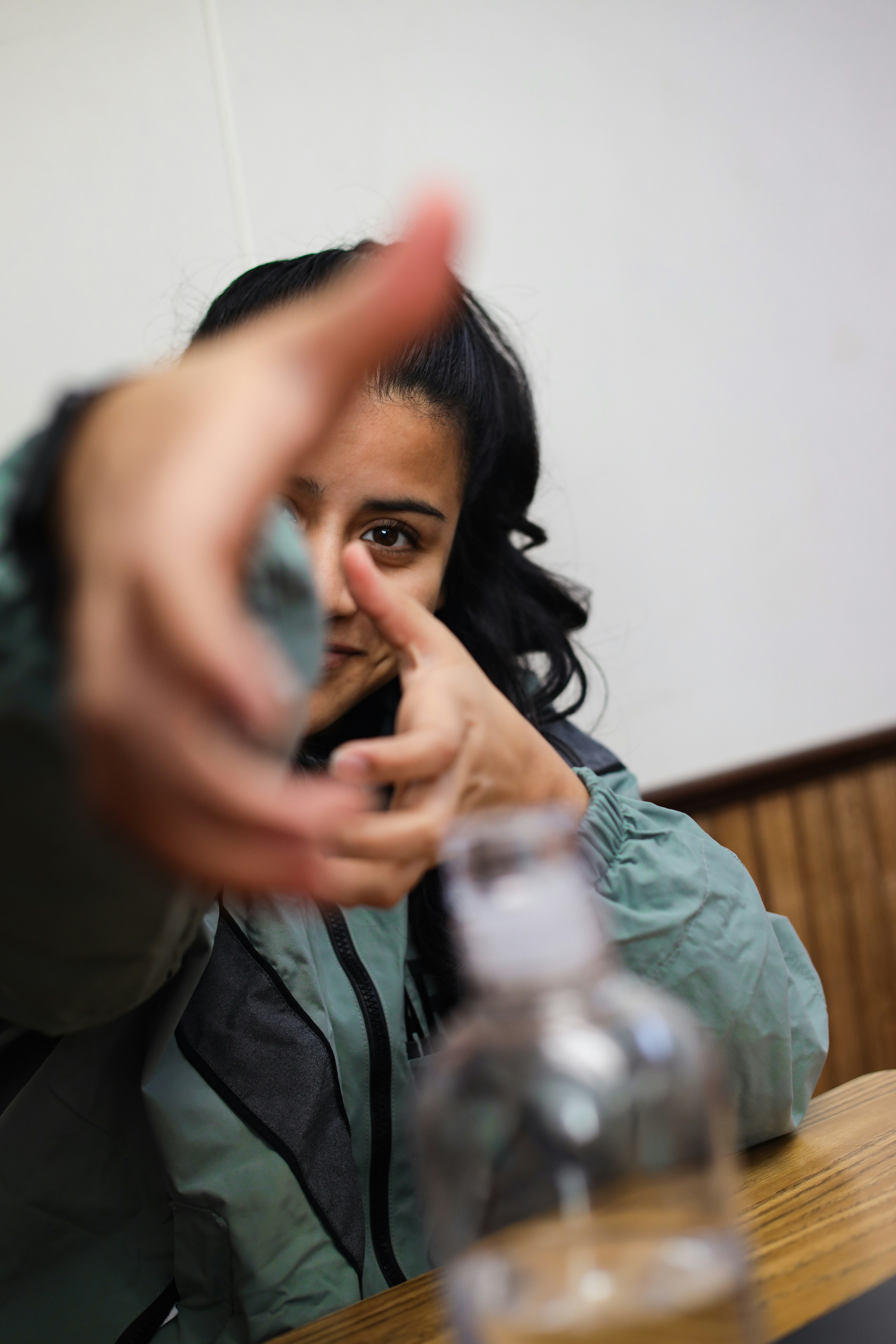 a woman sitting at a table making a hand gesture