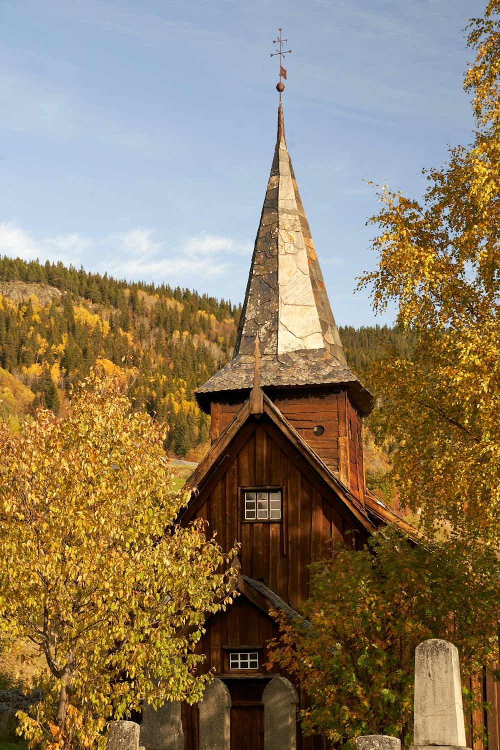a wooden church with a steeple surrounded by trees