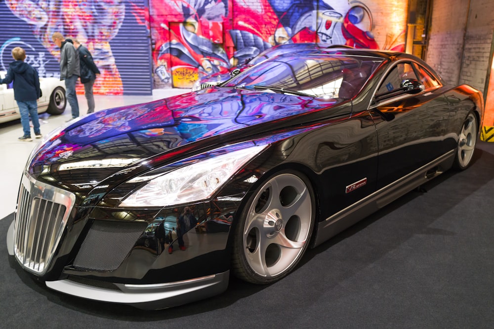 a black car parked in front of a graffiti covered wall