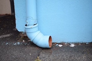 a blue pipe leaning against a blue wall