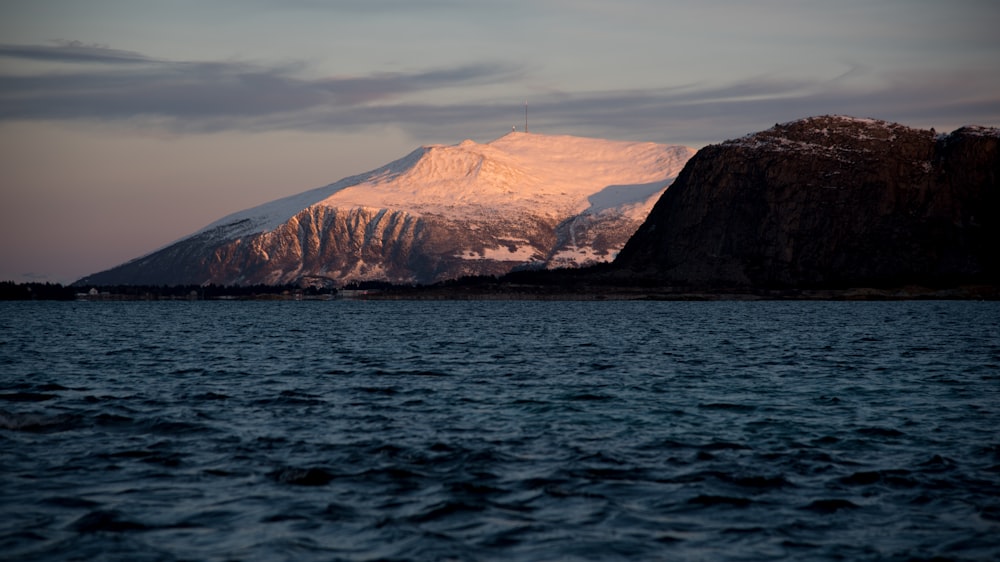 a snow covered mountain sitting above a body of water