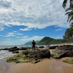 a man standing on top of a sandy beach next to the ocean