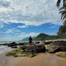a man standing on top of a sandy beach next to the ocean