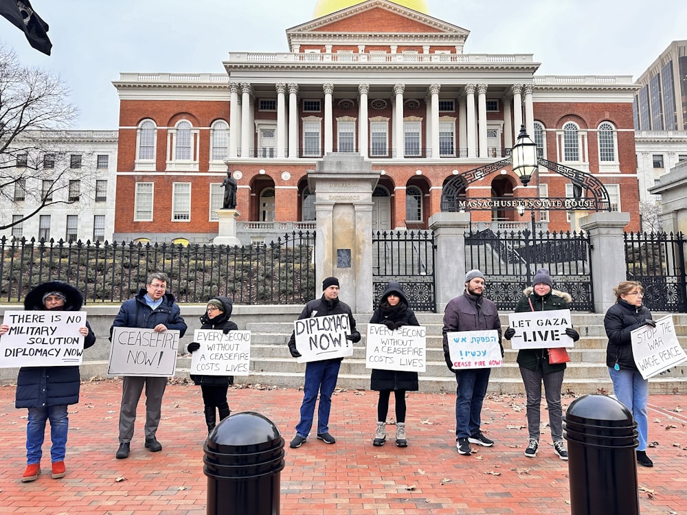 a group of people holding signs in front of a building