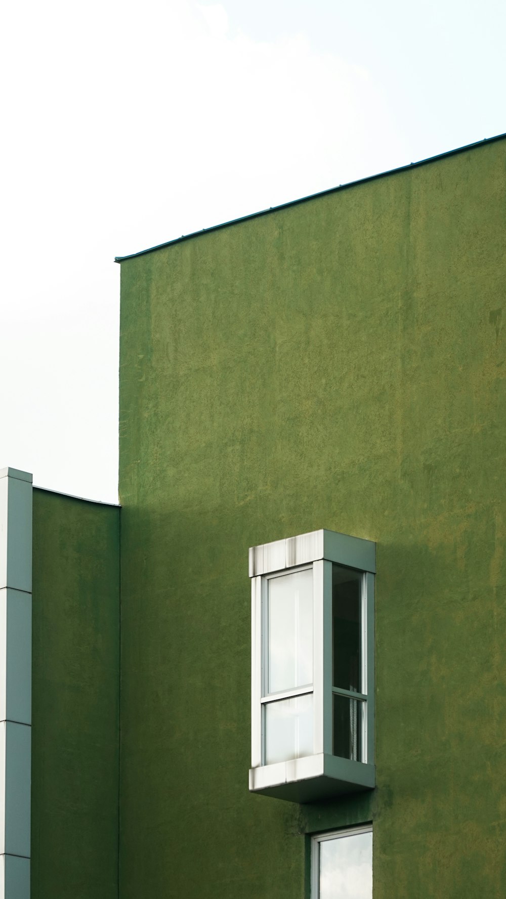 窓と空を背景にした背の高い緑色の建物