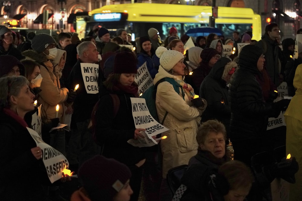 a large group of people holding candles and signs