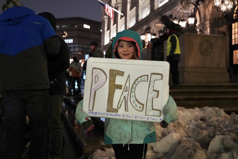 una bambina che tiene in mano un cartello che dice pace