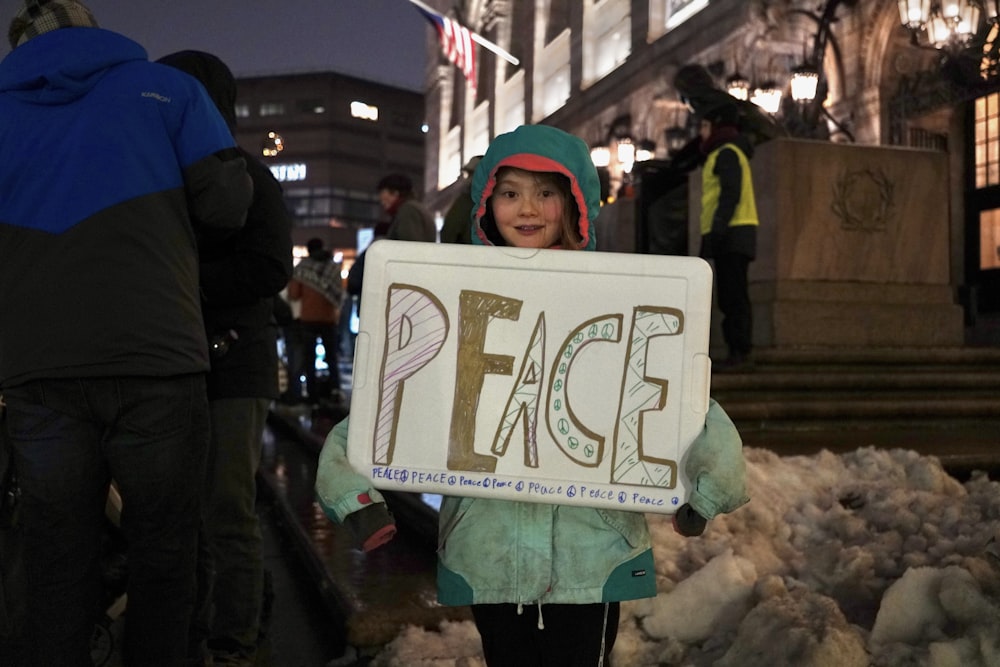 Ein kleines Mädchen hält ein Schild mit der Aufschrift "Frieden"