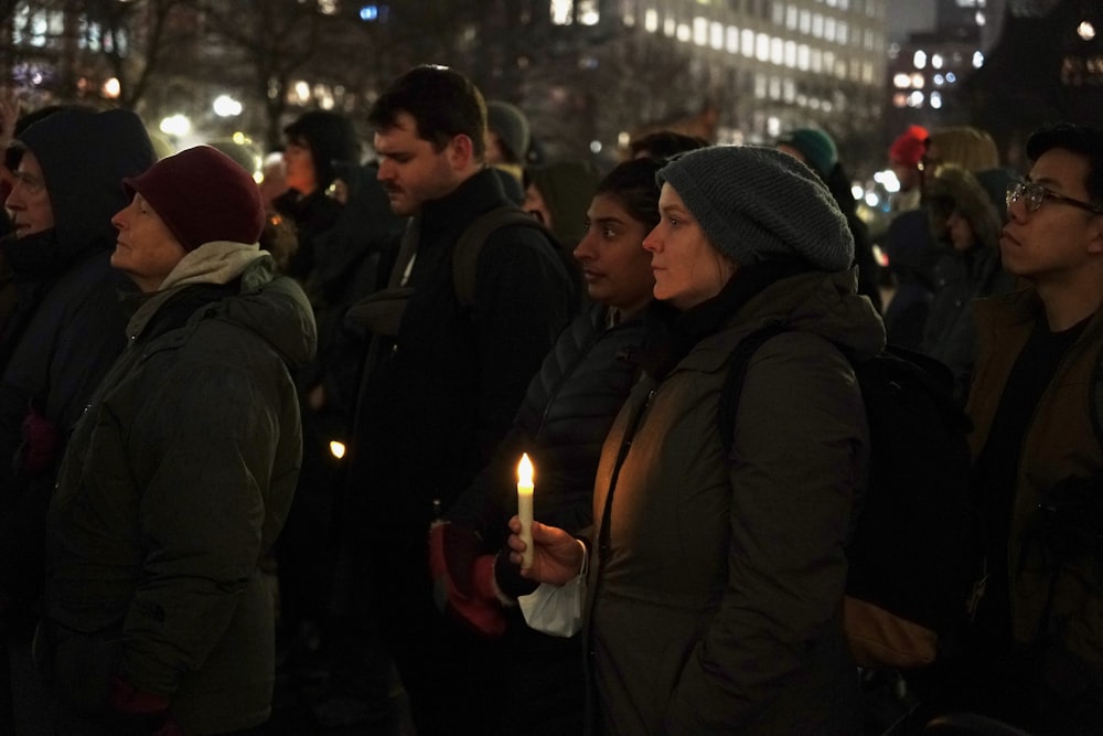 a group of people standing around each other holding a candle