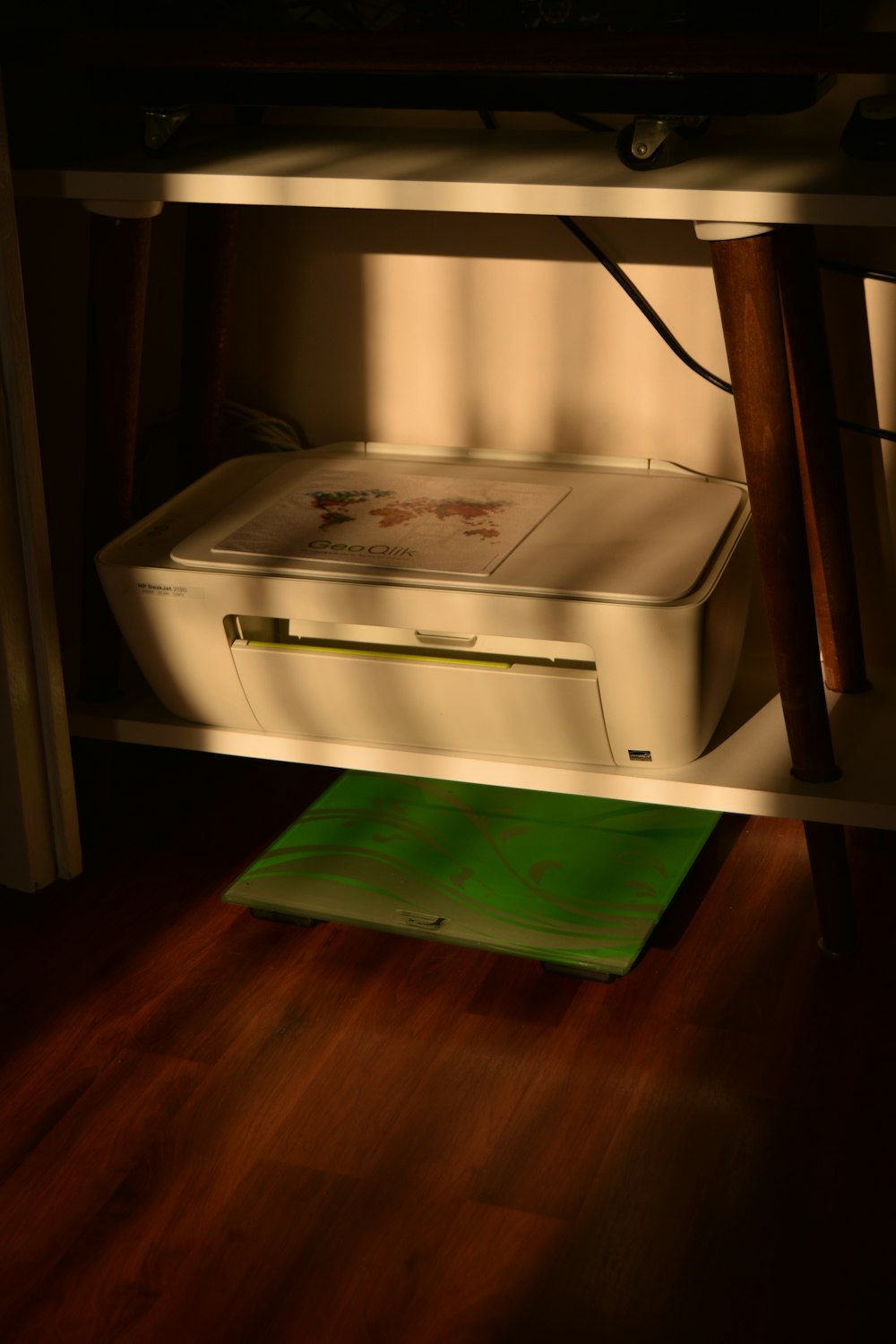 a white printer sitting on top of a wooden desk