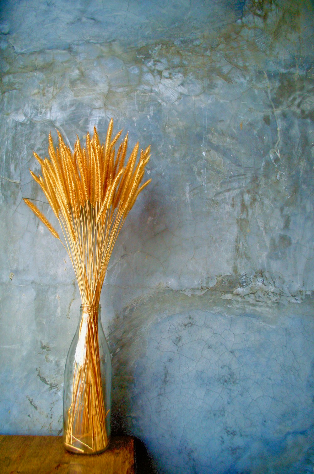 a glass vase filled with yellow straws on top of a wooden table