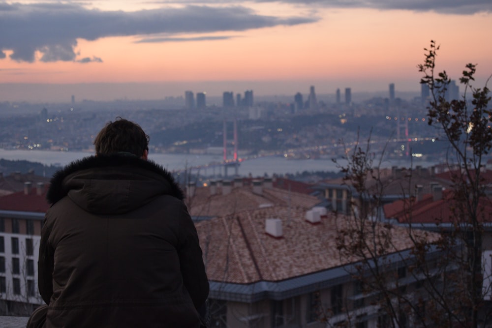 a man standing on top of a roof looking at a city