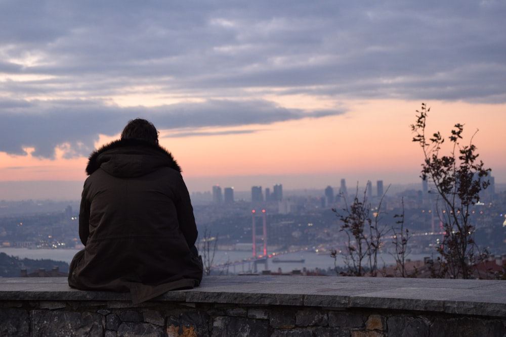 a person sitting on a wall looking at the city