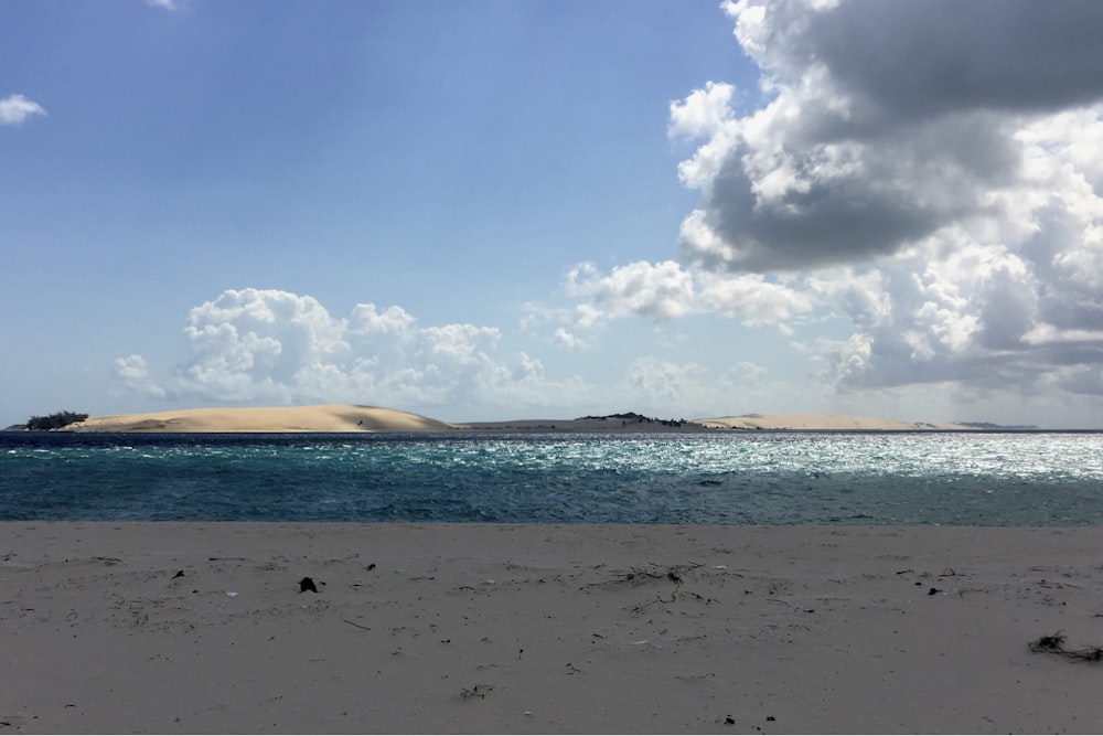 a sandy beach with a small island in the distance