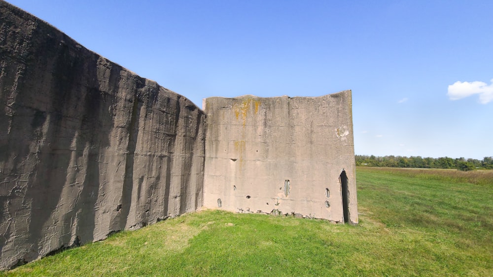 a large stone wall in the middle of a grassy field