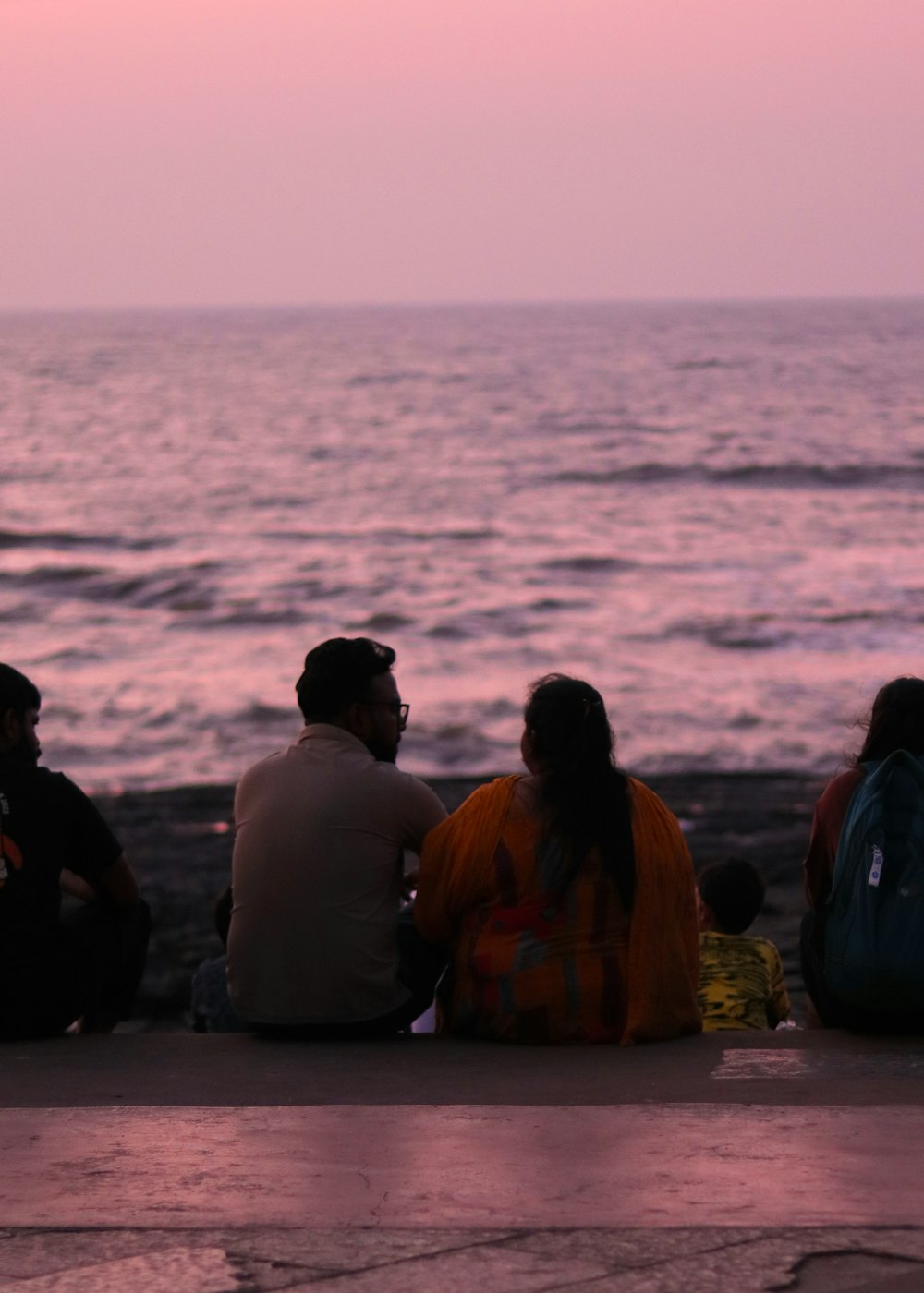 a group of people sitting next to each other near the ocean