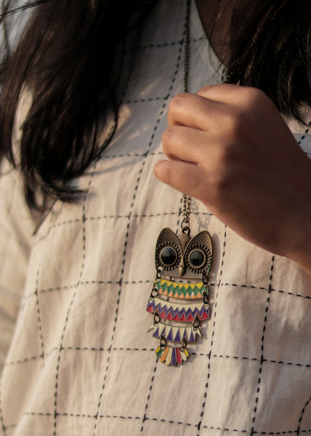 a close up of a person wearing an owl necklace