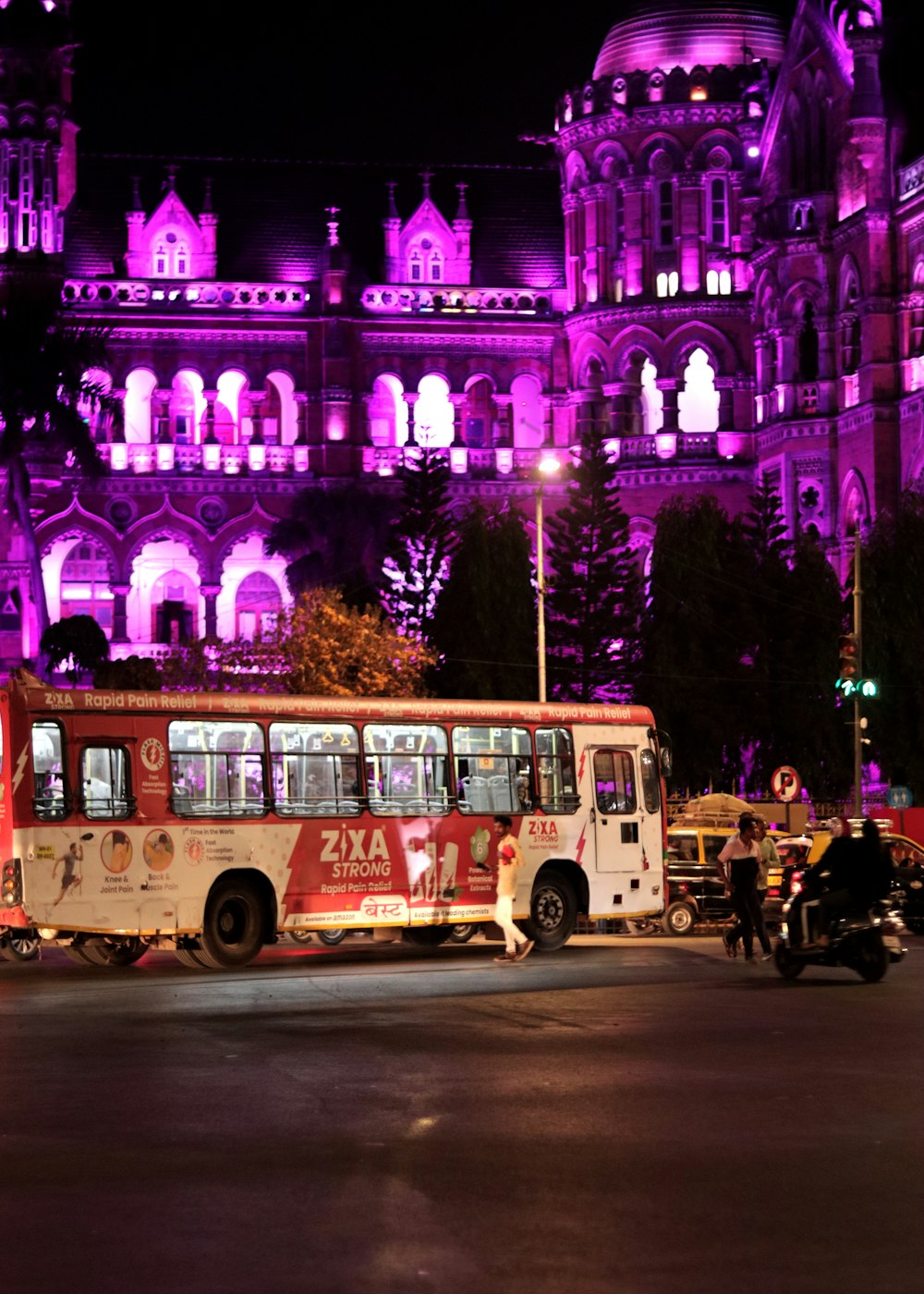 a red and white bus driving down a street next to a tall building