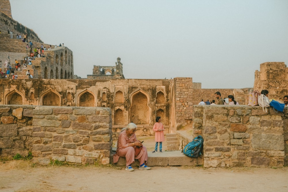 a couple of people sitting on a stone wall