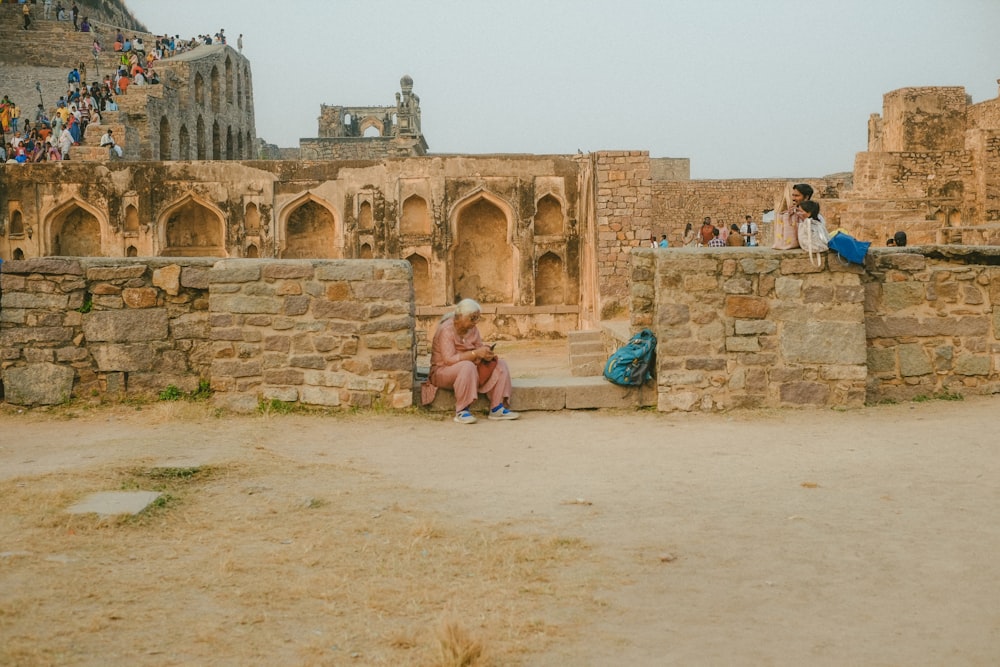 a woman sitting on a stone wall next to a building