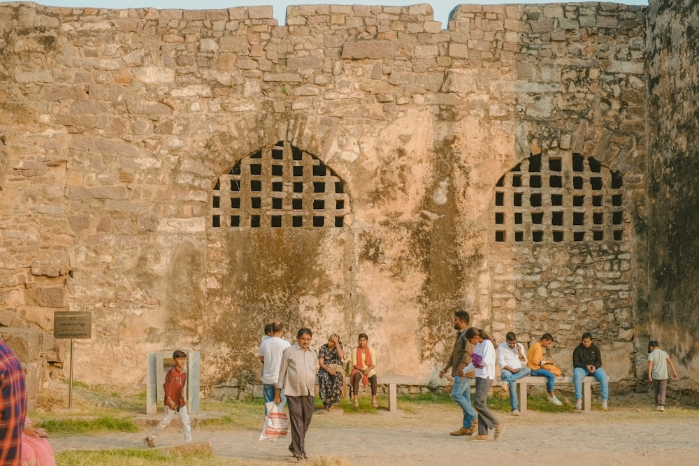 a group of people standing around a stone building