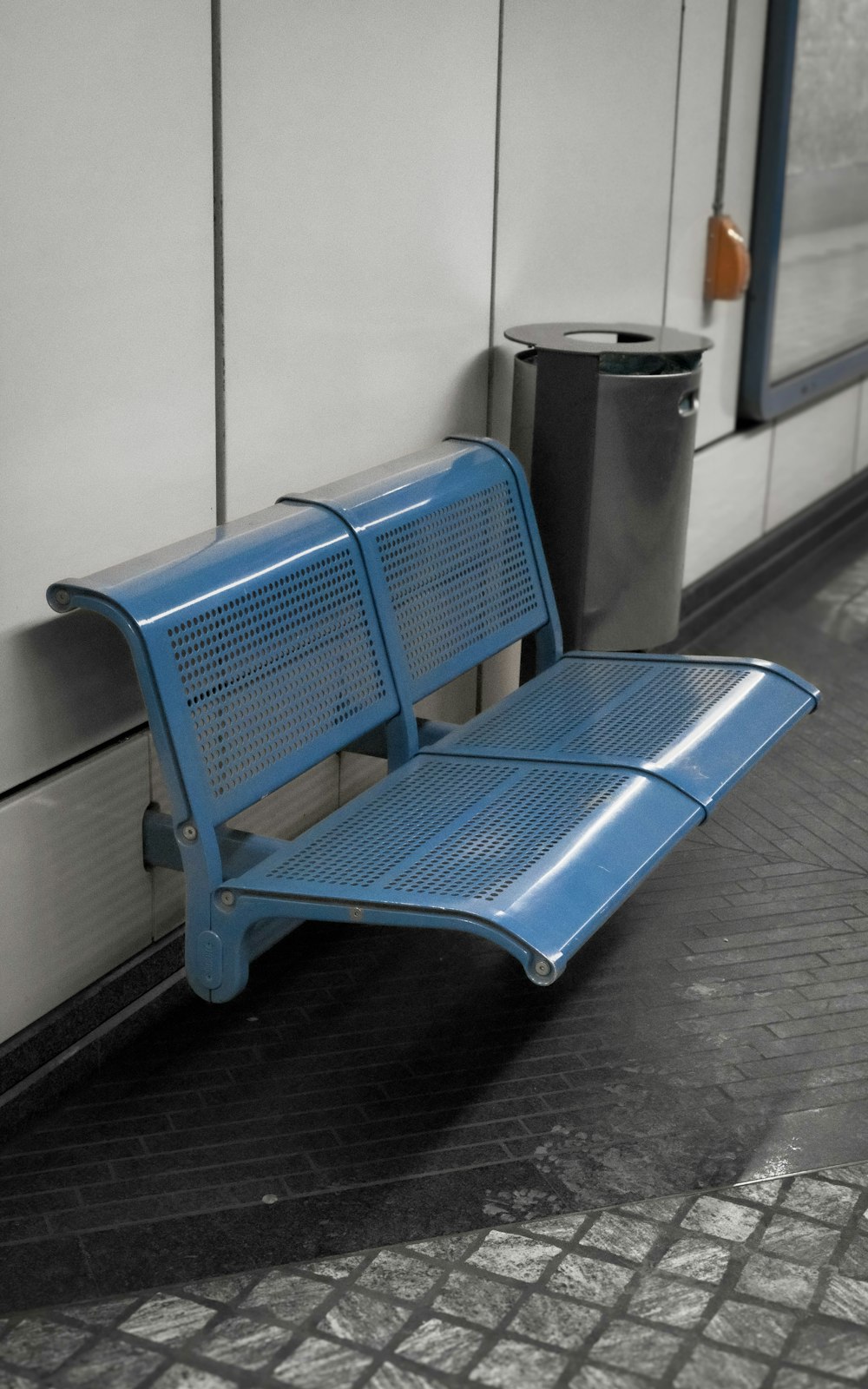 a blue bench sitting next to a white wall