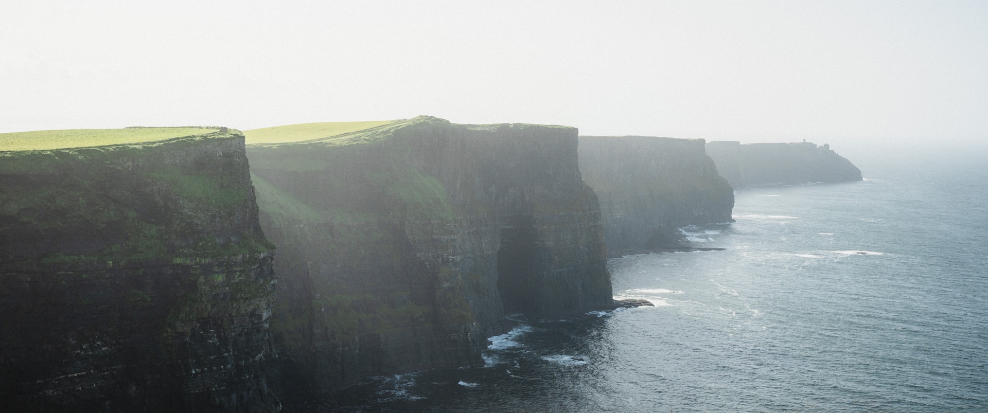 a large cliff with a grassy area on the side of it