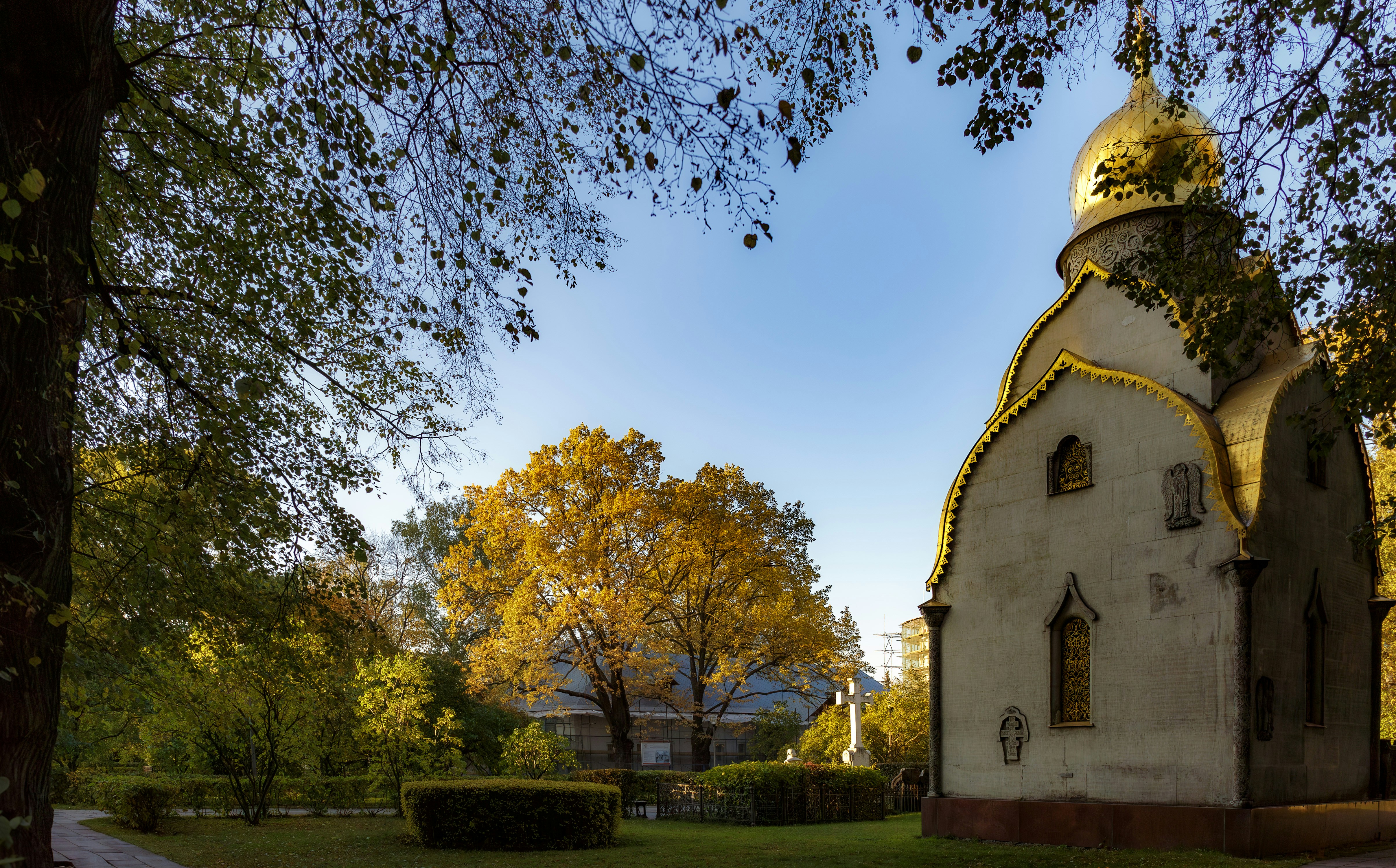 a small church with a golden roof in the middle of a park