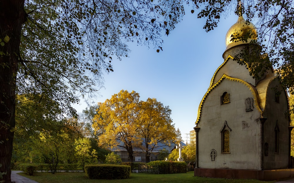 a small church with a golden roof in the middle of a park