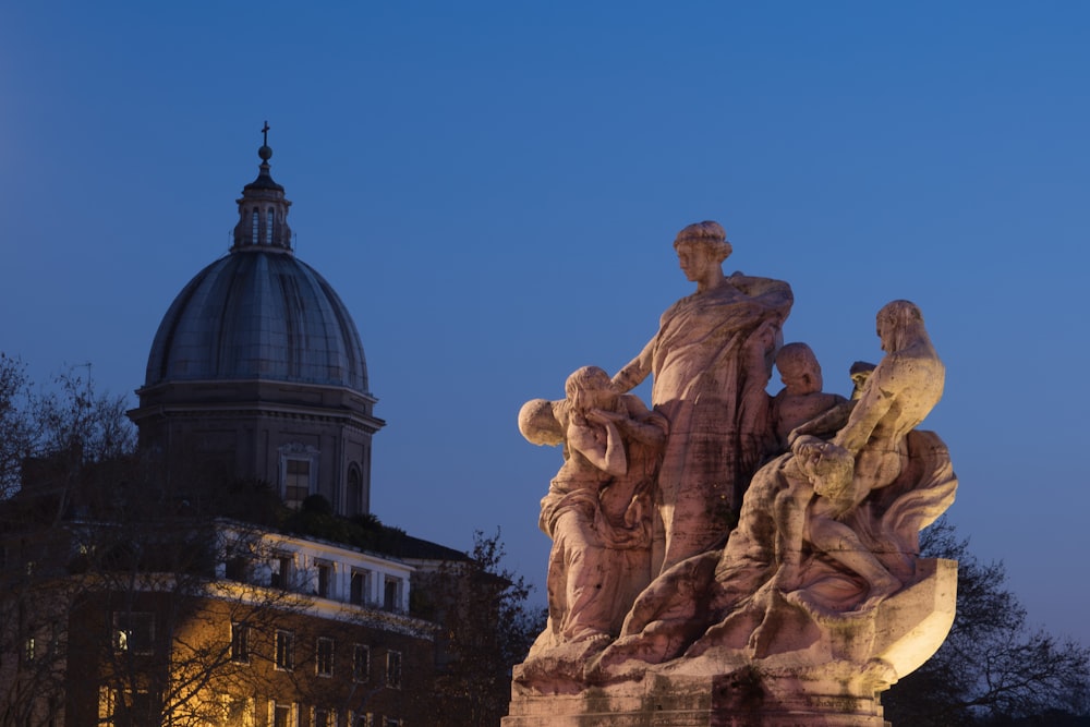 una statua di fronte a un edificio con una cupola sullo sfondo