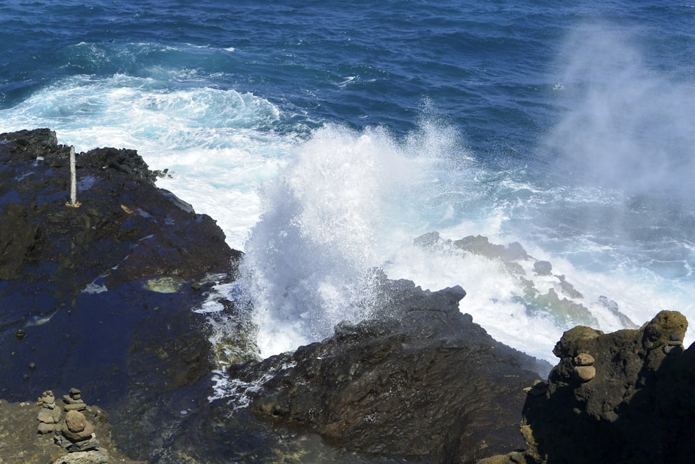 a wave crashes into the rocks near the ocean