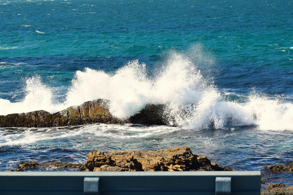 a bench sitting on top of a rocky beach next to the ocean