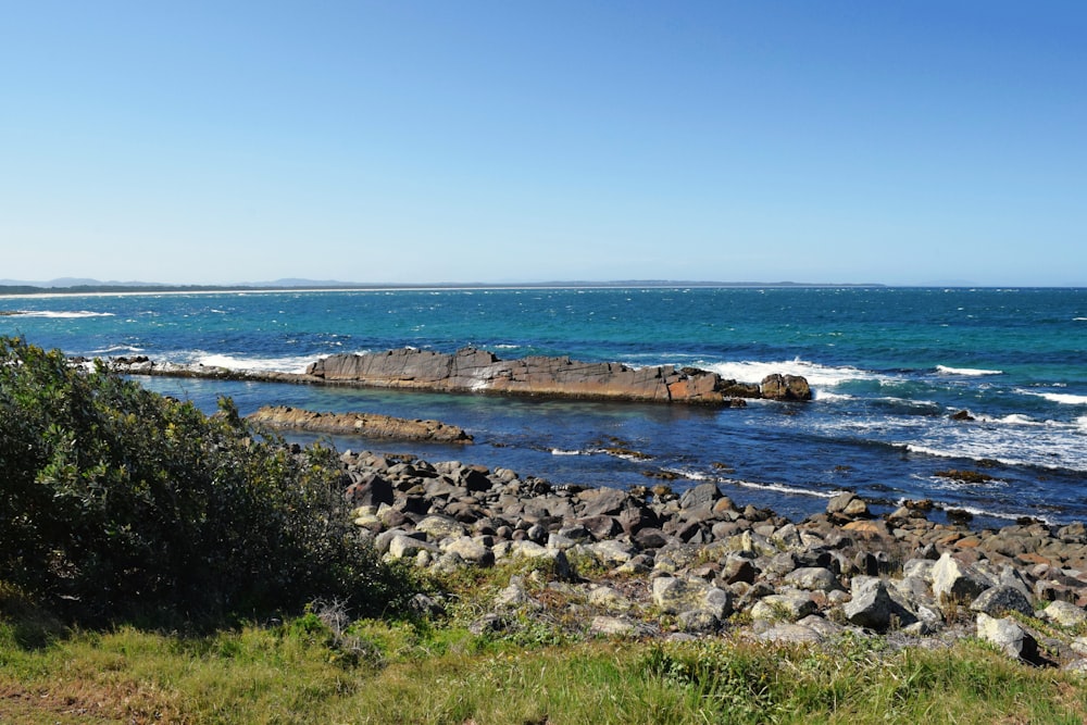 a rocky beach with a body of water in the background