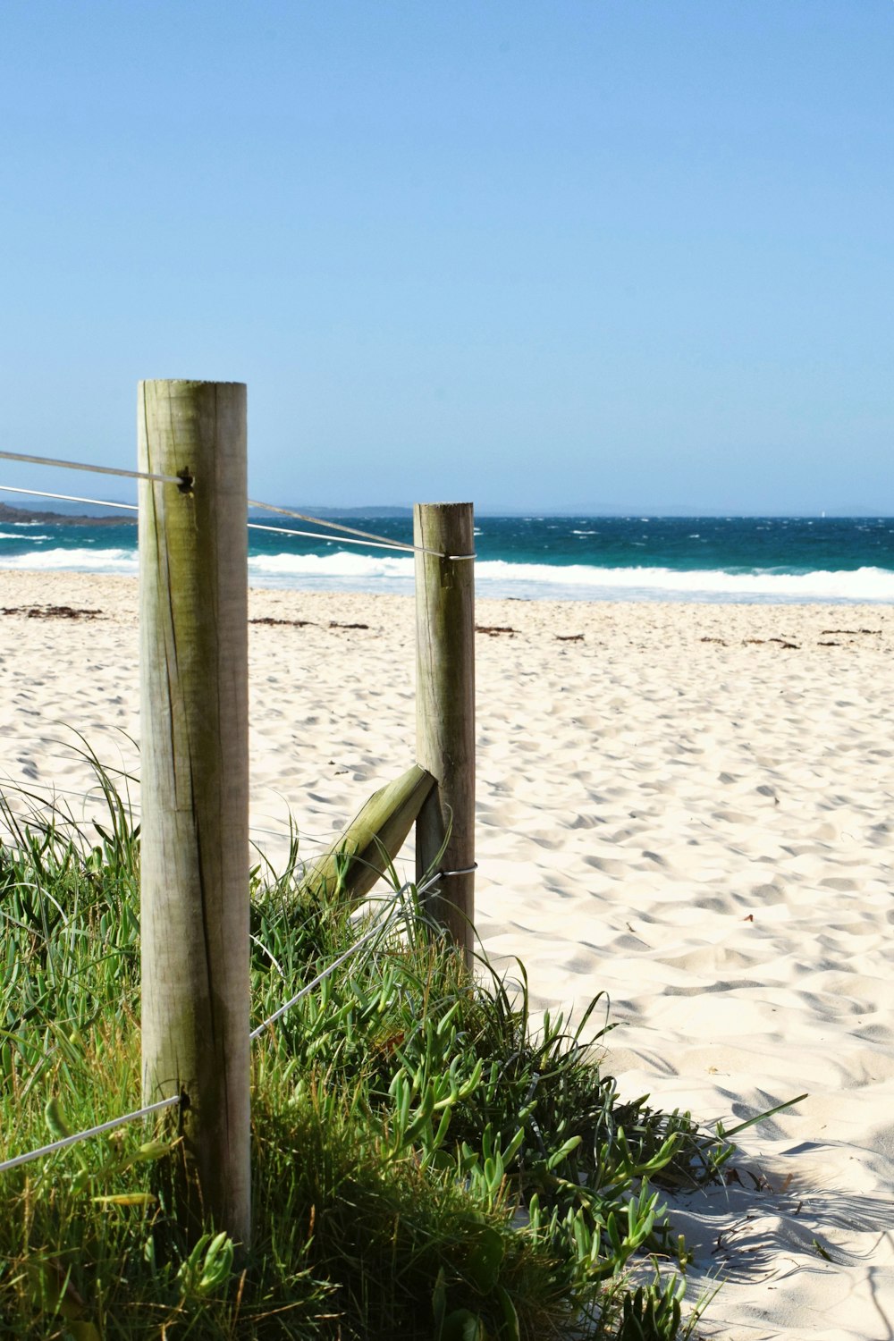 a wooden fence on a beach near the ocean