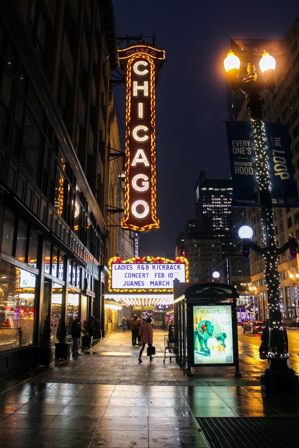 a city street at night with people walking on the sidewalk