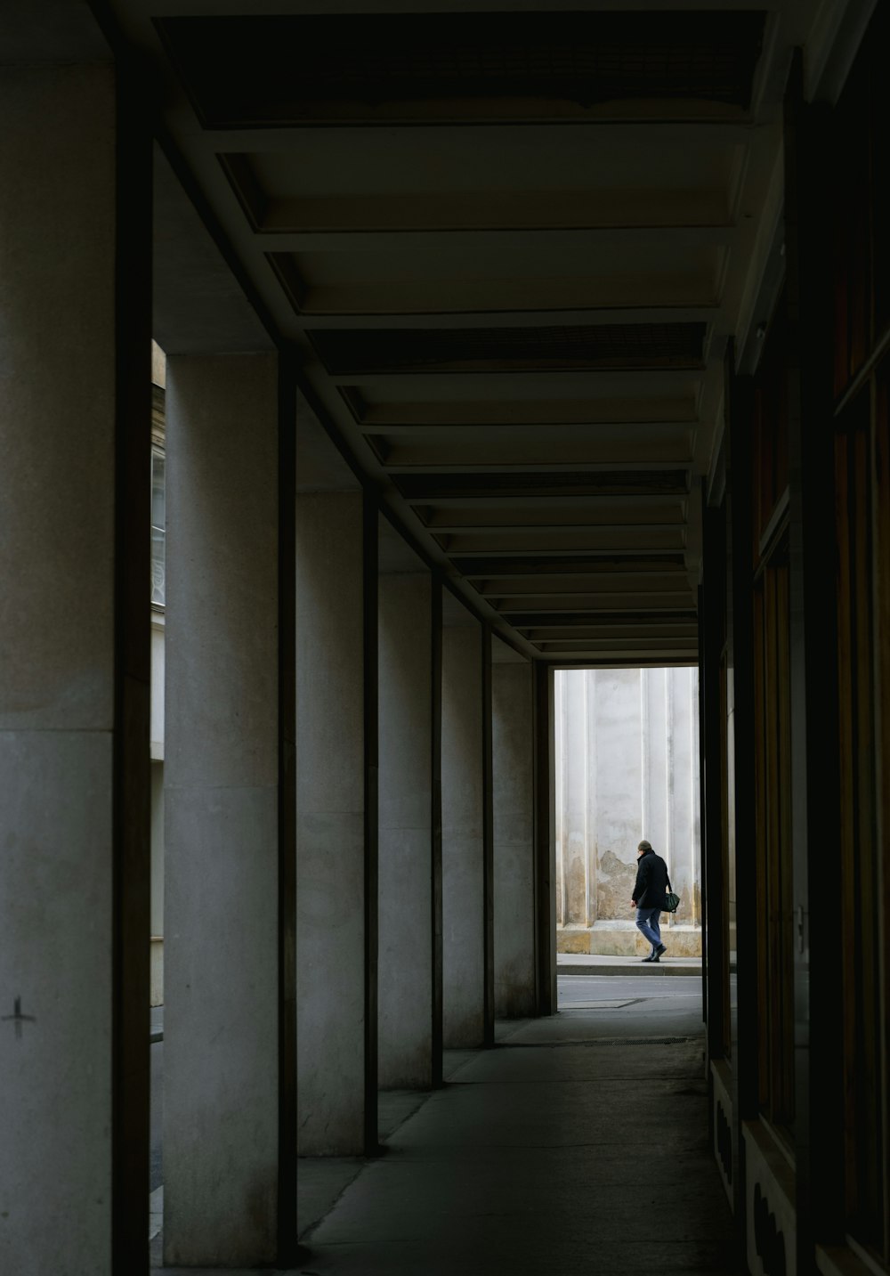 a person walking down a long hallway between two buildings