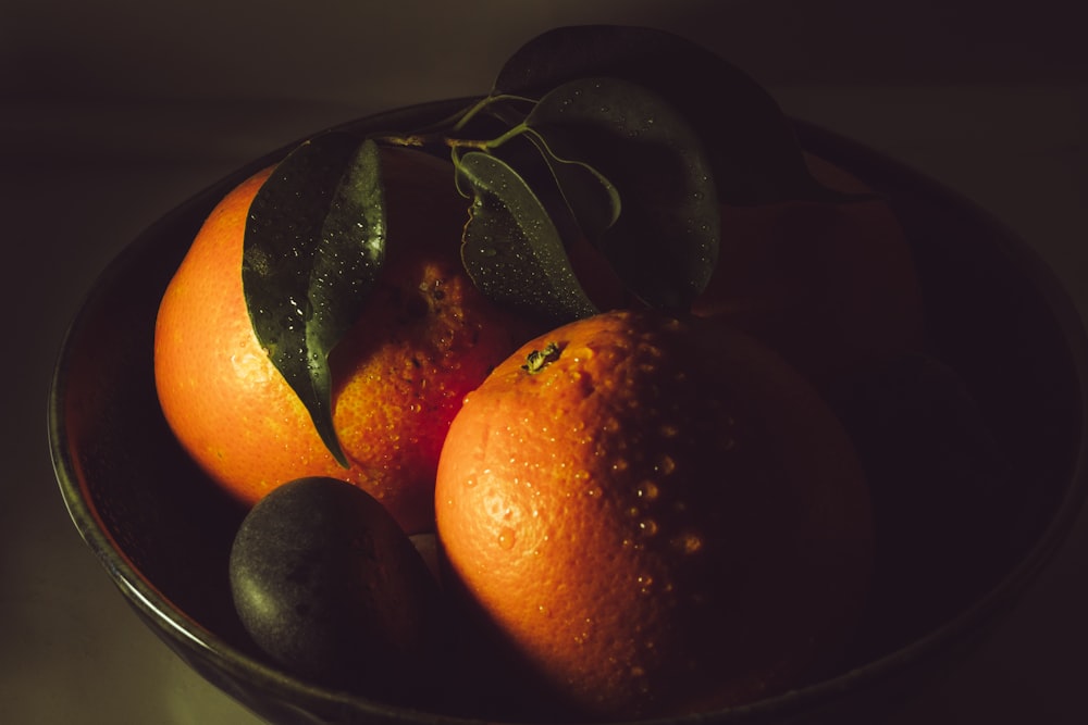 a bowl of oranges and avocados on a table