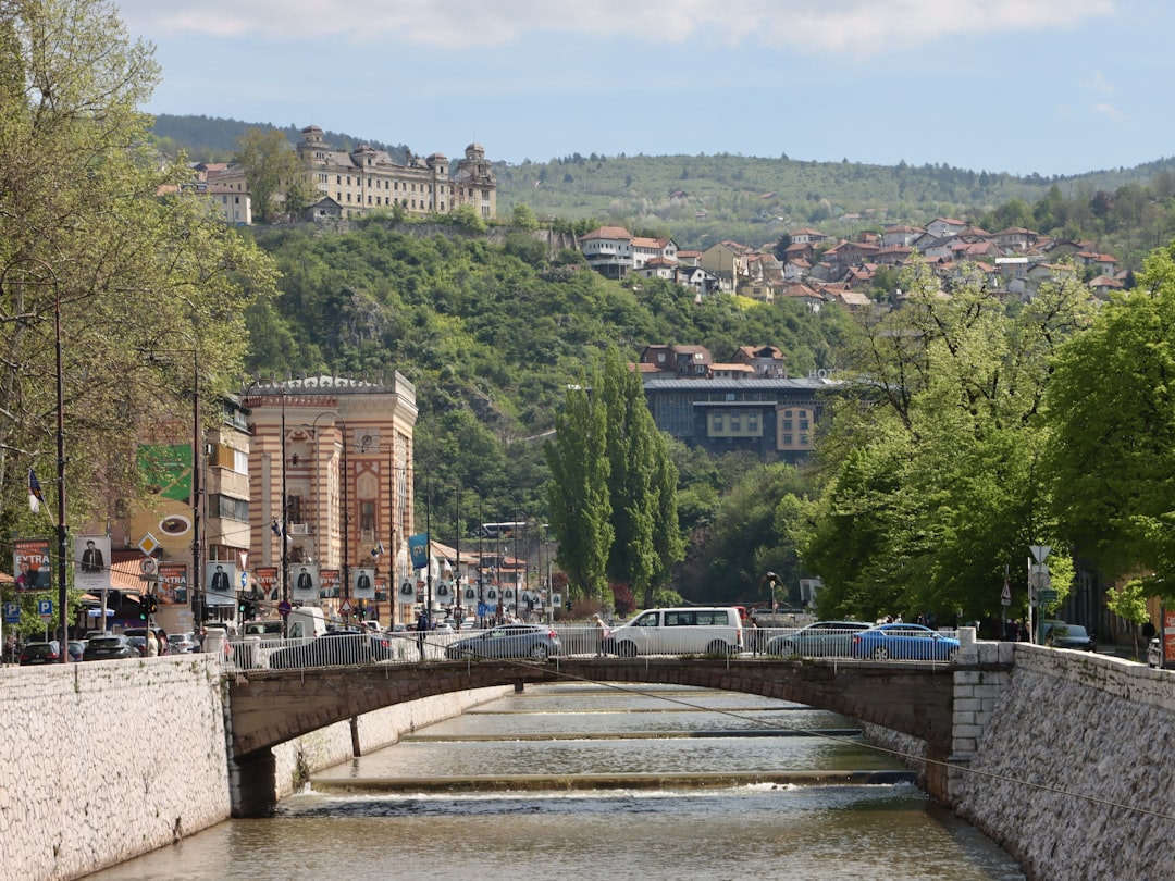 a river running through a city with a bridge over it, Sarajevo🇧🇦