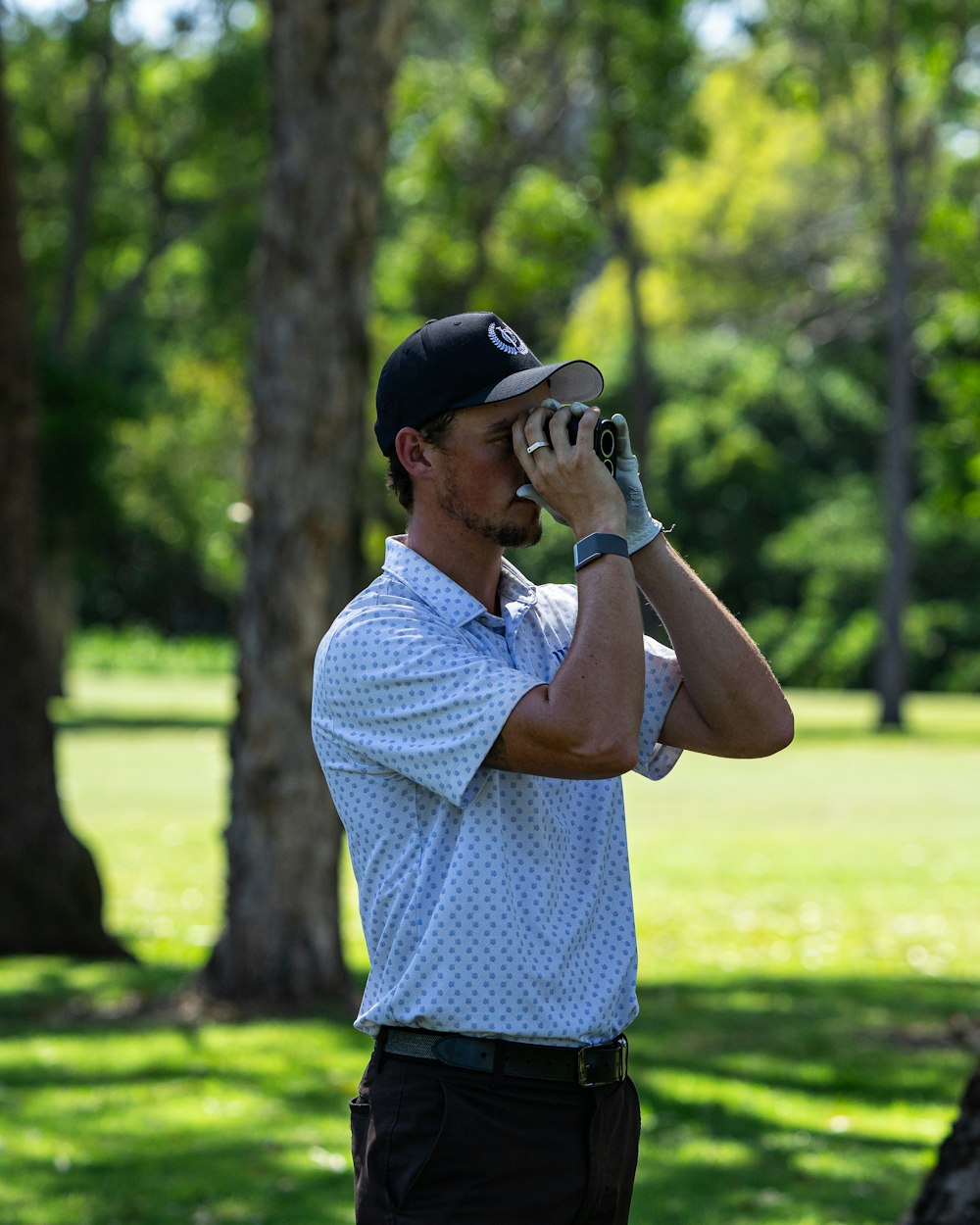 a man standing in a park looking through binoculars