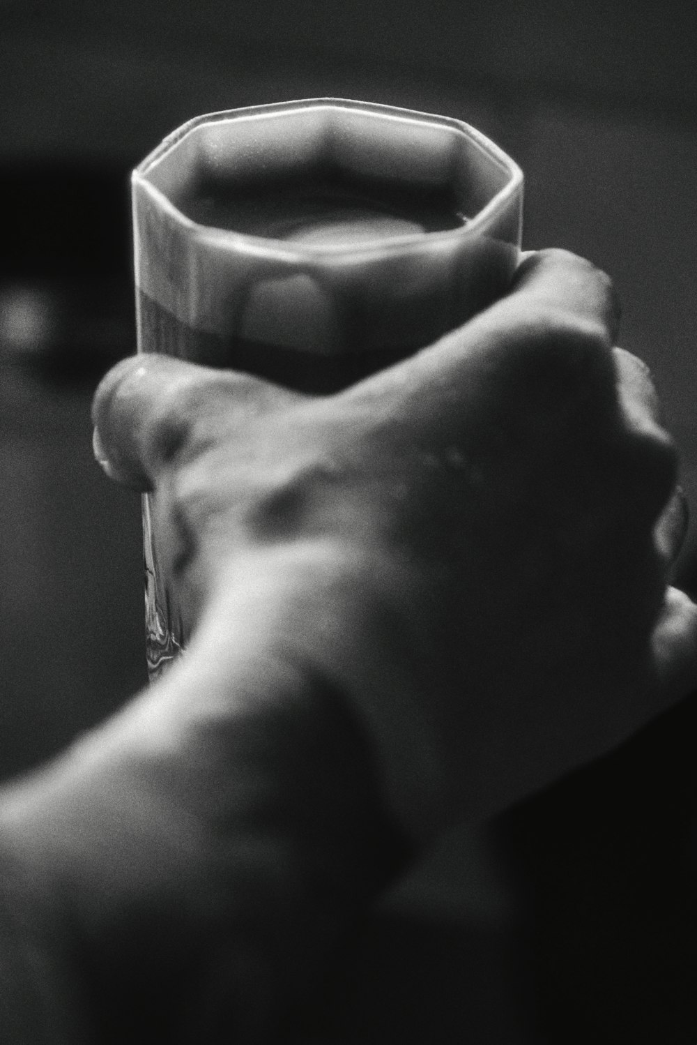a black and white photo of a person holding a glass