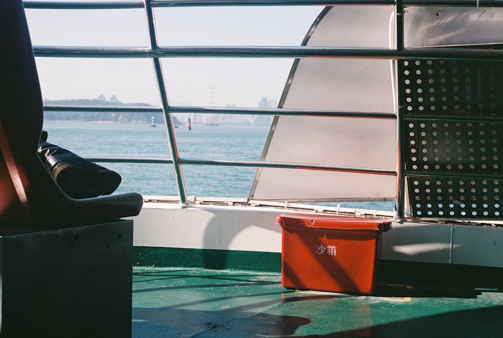 a red container sitting on the side of a boat