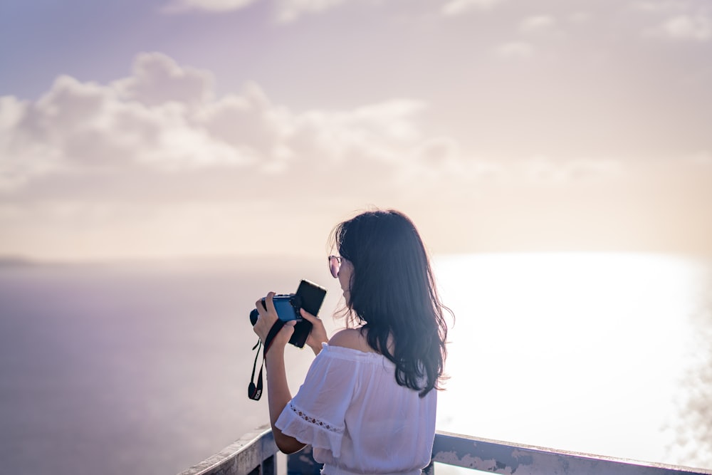 a woman taking a picture of the ocean