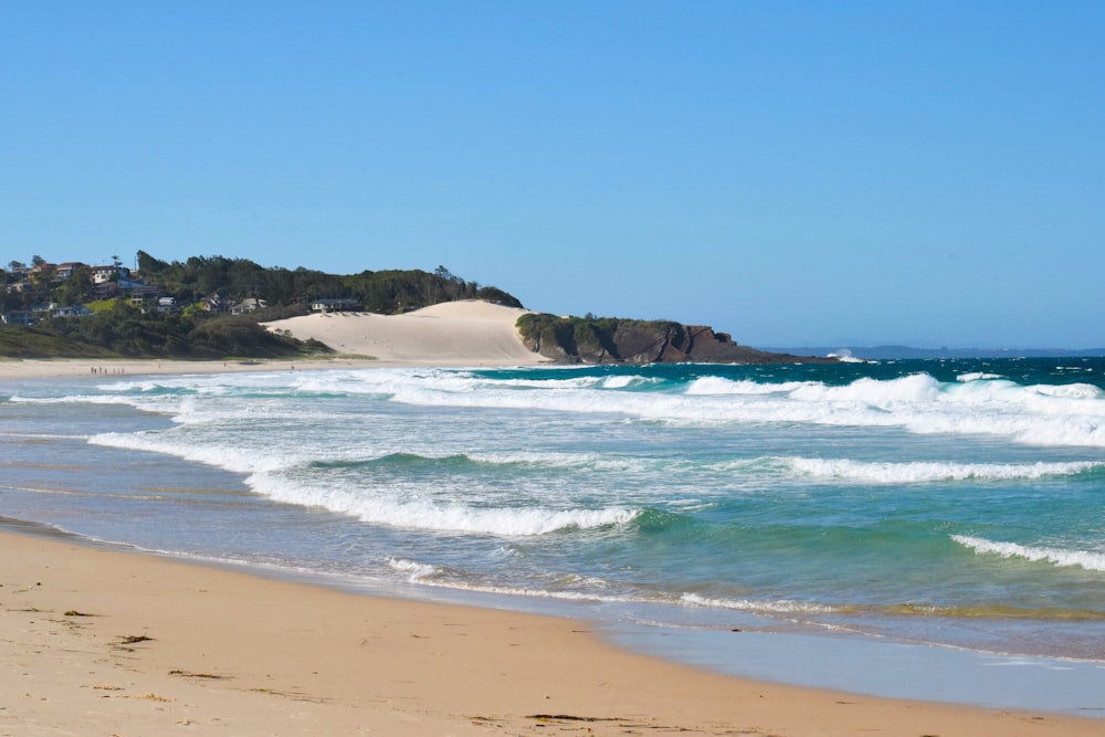 a sandy beach with waves coming in to shore