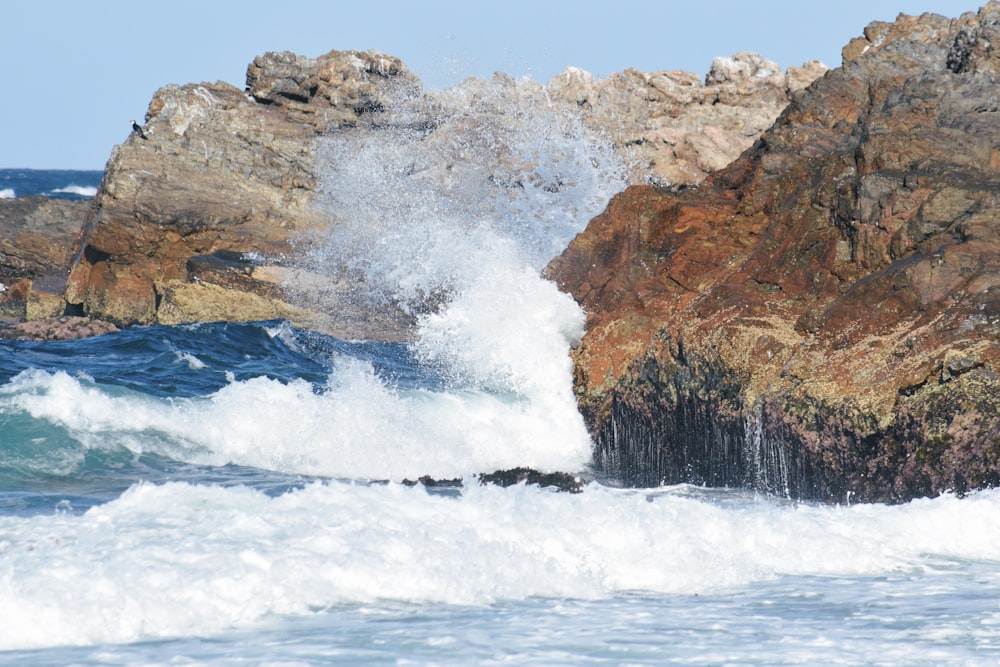 a wave crashes against the rocks on the ocean