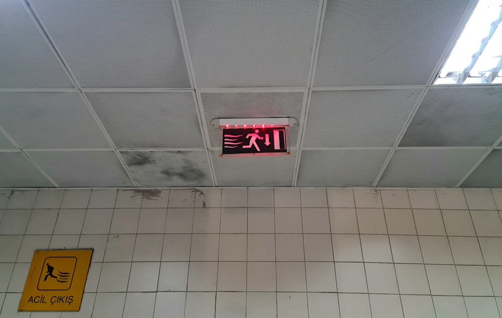 a bathroom with a tiled floor and a red neon sign