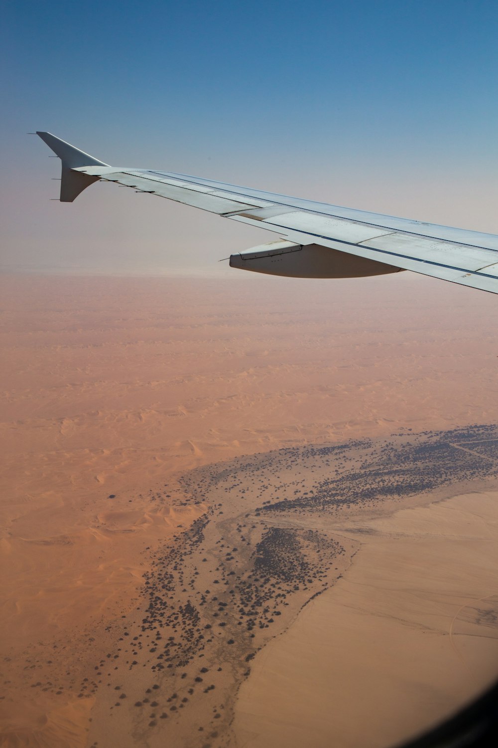 the wing of an airplane flying over a desert