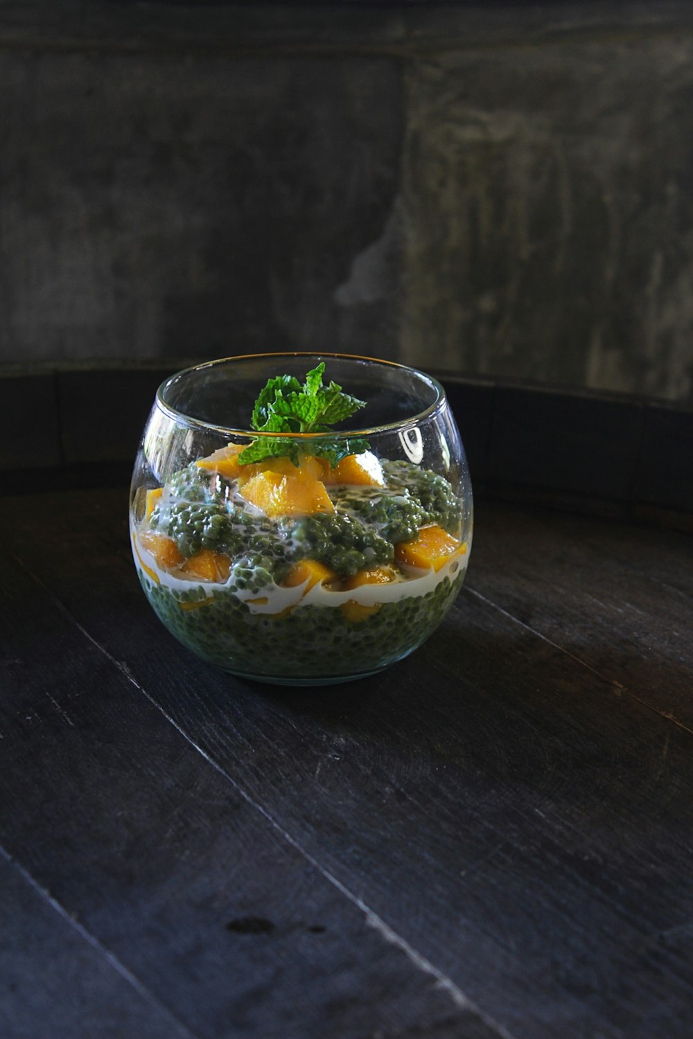 a glass bowl filled with food on top of a wooden table