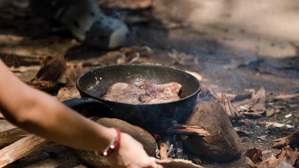 a person is cooking food over a campfire